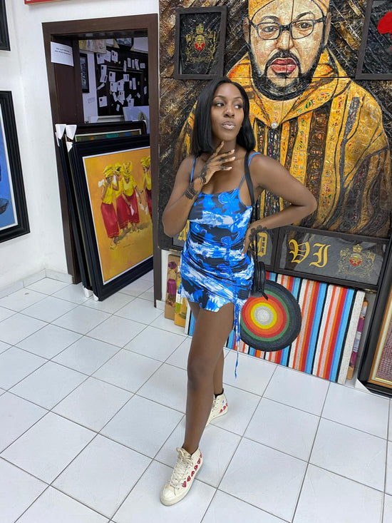 picture of a woman in a blue dress standing in front of artwork