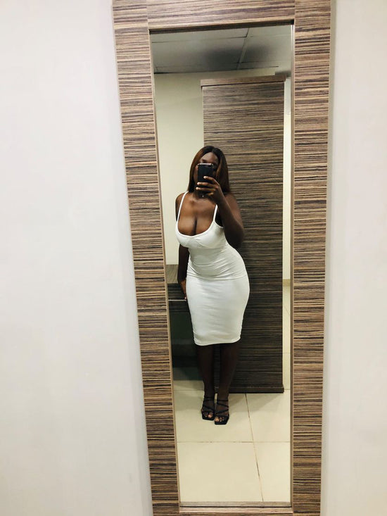 Picture of a woman in a white dress posing in front of a mirror